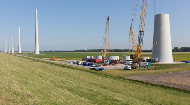 Dutch farmland with construction site of enormous new wind turbines